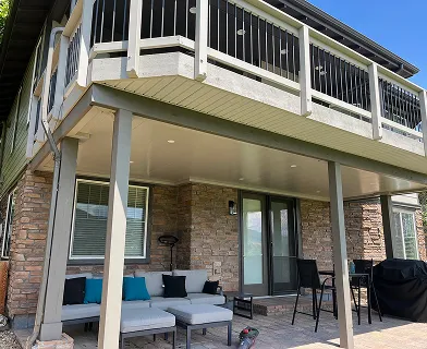 Covered patio with outdoor furniture under an upper-level deck
