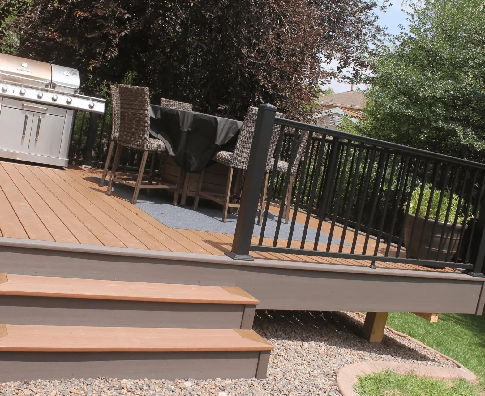 Ground-Level Deck Connected to a Colorado Backyard Ground-level composite deck with black railing and an outdoor BBQ area connected to a Colorado backyard