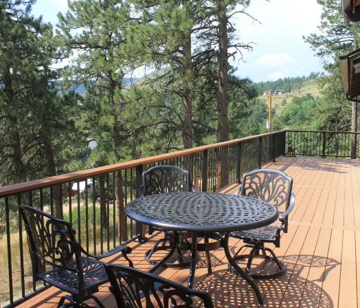Wooden deck with a patio dining set among pine trees