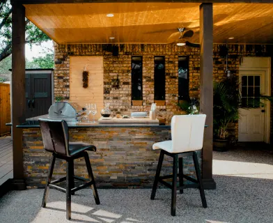 Outdoor kitchen with a stone bar and bar stools
